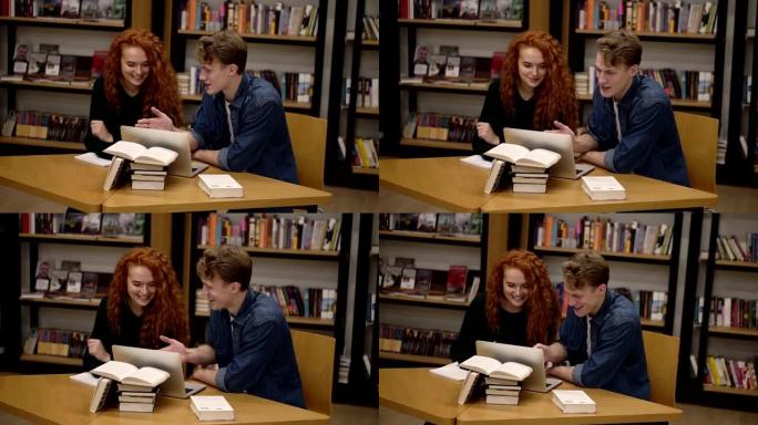 年轻的男女学生使用笔记本电脑交谈，解释课程在图书馆一起学习。积极讨论坐在木桌旁的东西。慢动作