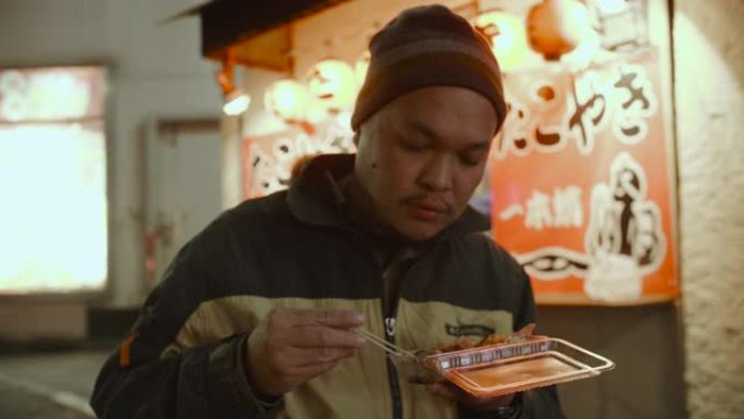 亚洲男子吃日本食物章鱼烧。