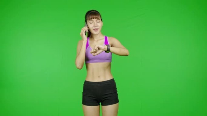 一位健康女性给她坏了的手表打电话寻求技术支持，绿色屏幕，很高兴他们修好了。亚洲女运动员穿着紫色的衣服