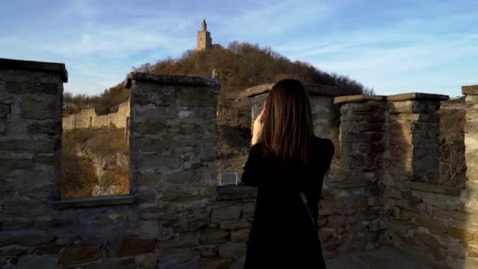 穿着黑色夹克的黑发女孩在保加利亚被称为Tsarevets的中世纪老据点享受阳光明媚的秋日
