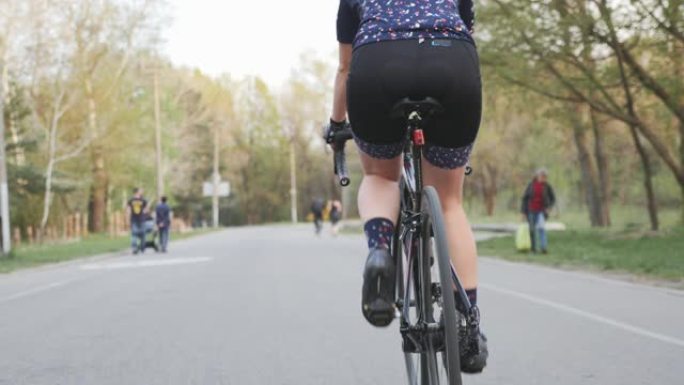 骑自行车的女骑车人的腿踩着自行车。后退射击。自行车上的腿部肌肉。自行车概念。慢动作
