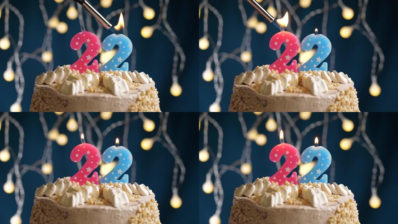 蓝色背景上有22号粉色蜡烛的生日蛋糕。蜡烛着火了。慢动作和特写视图