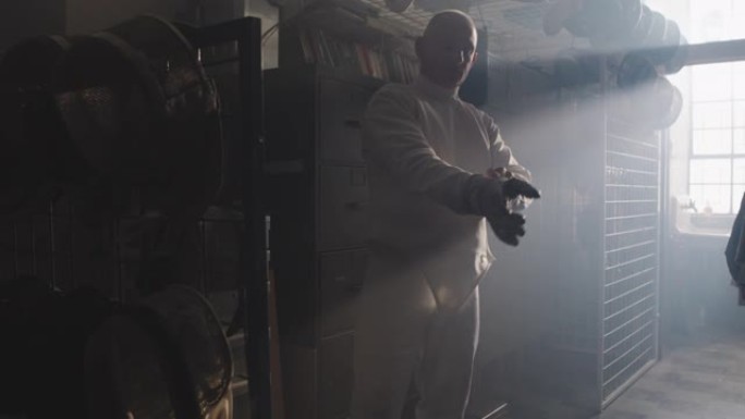 一名击剑运动员在有雾的设备室内戴上击剑手套和面罩