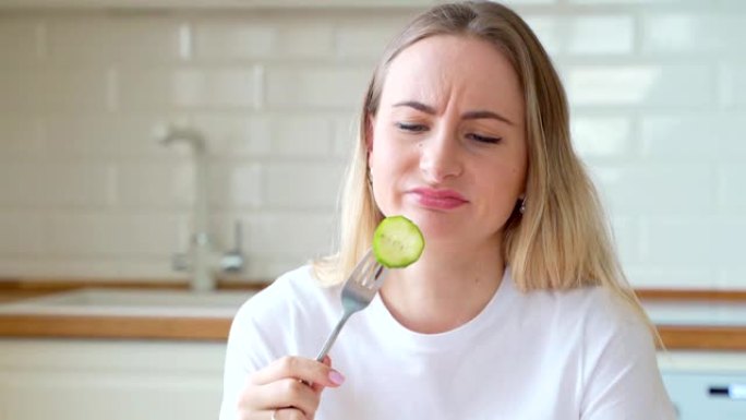 沮丧的饮食女人在盘子里吃黄瓜