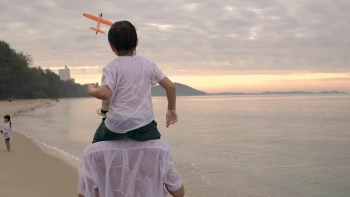 亚洲父子一起玩飞机玩具日落快乐家庭户外散步