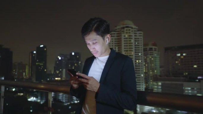 亚洲男子在午夜街头城市使用智能手机