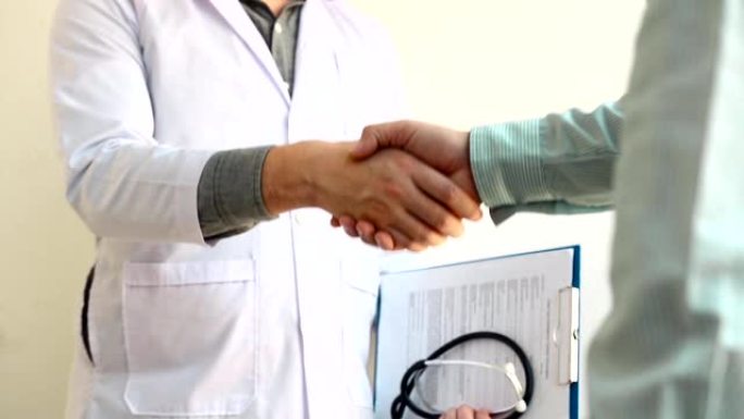 医生和病人祝贺在医院办公室前握手。