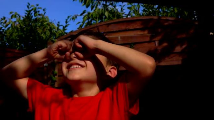 小男孩用手指做双筒望远镜的手势，看着天空