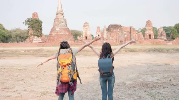 亚洲两个女人兴奋地牵着手，一起奔跑，张开双臂拥抱在泰国世界遗产城市大城府。自由女人在老城度假旅行。慢