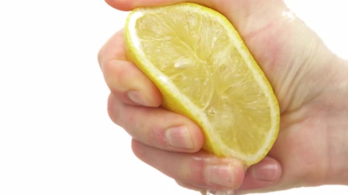 新鲜的柑橘汁从榨柠檬中滴下来。男性手工挤压柑橘类水果的特写。孤立，在白色背景上