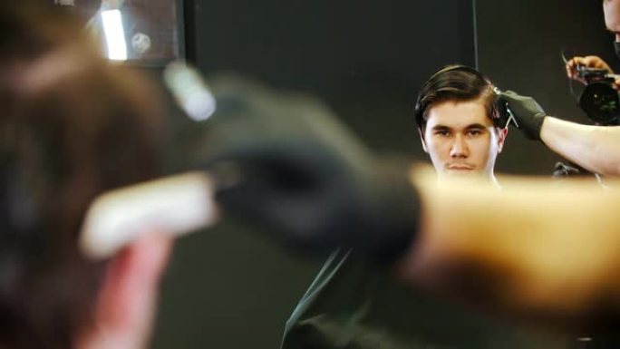 理发师在太阳穴上剪掉年轻男子客户的湿头发 -- 镜子反射