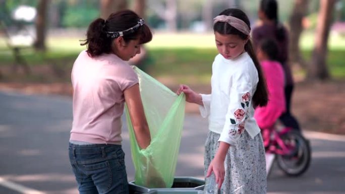 女孩和朋友帮助清理并将纸张扔进垃圾箱，捡起或垃圾收集地面上的垃圾