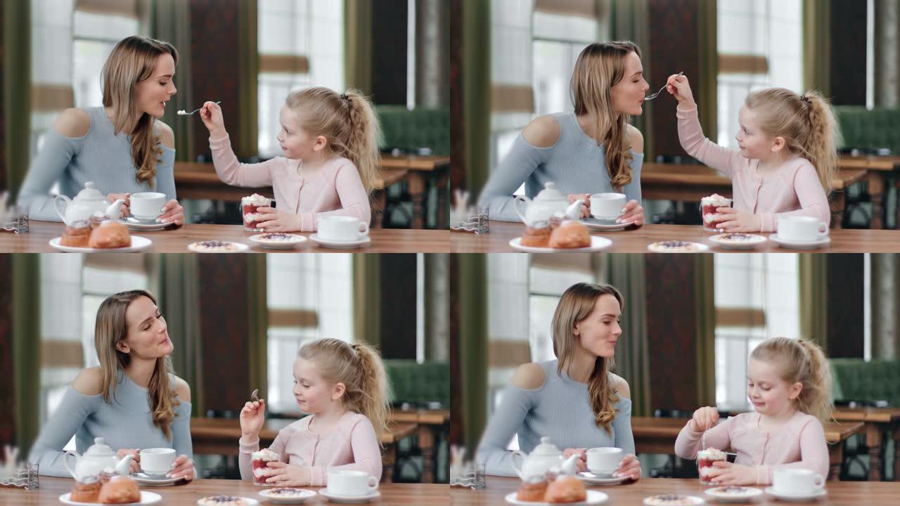 充满爱心的顽皮女儿用鲜奶油喂养微笑的母亲甜点。红色相机上的中等镜头