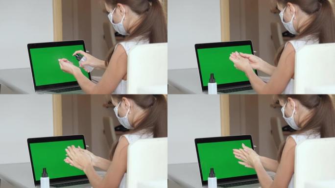 女人用绿屏在笔记本电脑前消毒双手