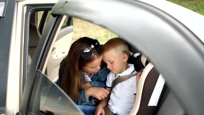 慈爱的母亲和儿子在车里的肖像，男孩系着安全带