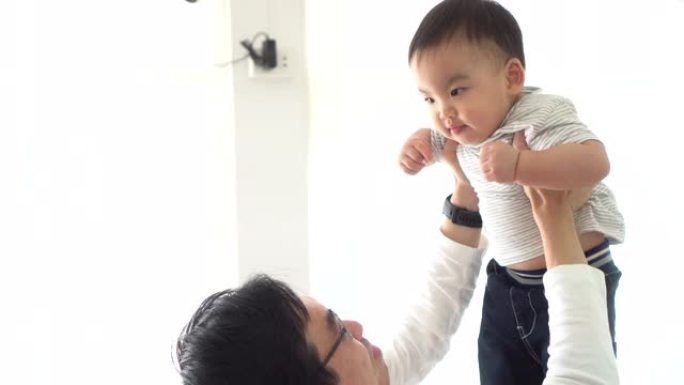 亚洲父亲举起自己的小儿子在空中飞行