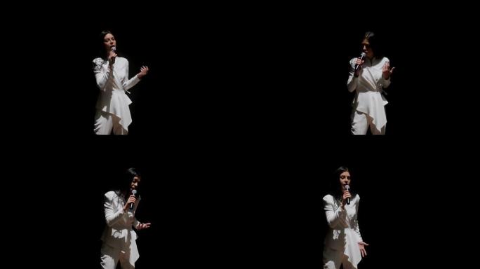 一个穿着白色西装的歌手在舞台上的特写镜头，在黑色背景上唱歌。