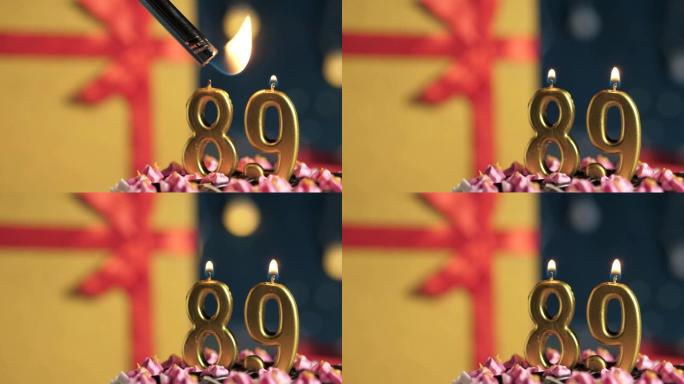 生日蛋糕89号点火器燃烧的金色蜡烛，蓝色背景礼物黄色盒子用红丝带绑起来。特写和慢动作