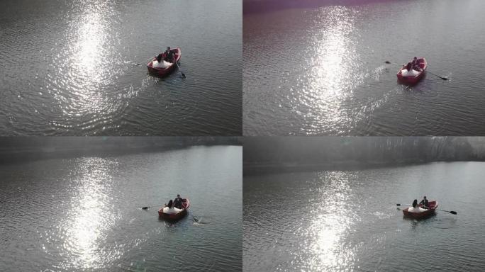 新娘在红船上游泳的空中镜头。明亮的太阳反射在湖中，形成反射和闪烁的眩光。