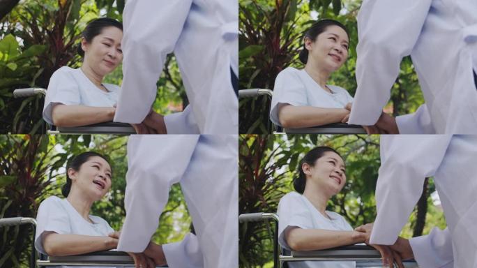 关爱之手，亚洲医生抱着花园背景的轮椅上的高级女性。快乐的微笑。
