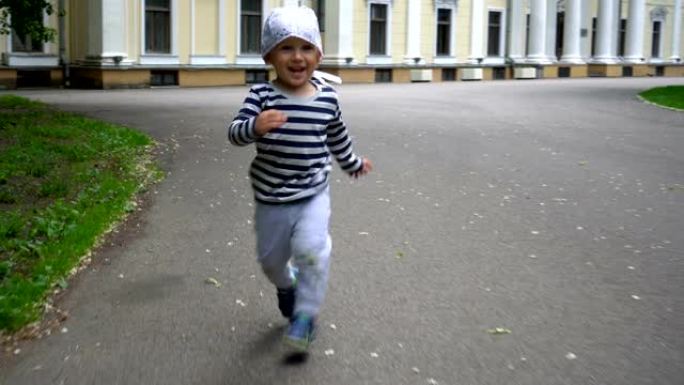 活跃的蹒跚学步的男孩在公园的柏油路上跑步。万向节运动镜头
