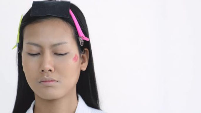 化妆师用白色背景的化妆品彩笔向美女展示脸颊区域的化妆过程