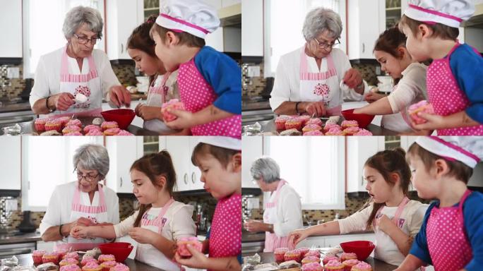 小女孩和男孩和祖母一起烹饪情人节松饼