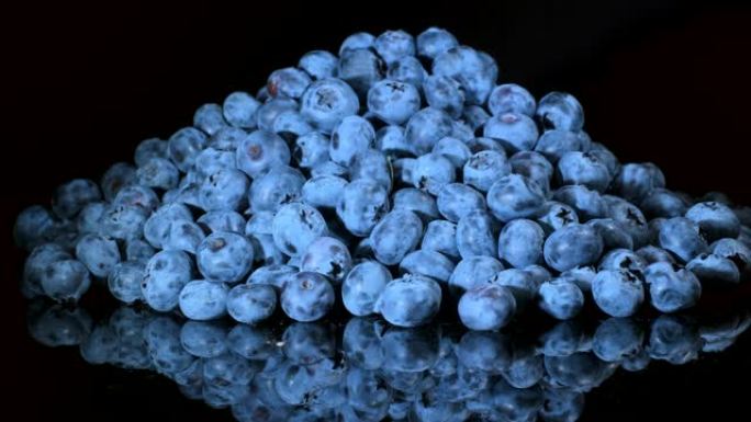 蓝莓在黑色玻璃上旋转反射。特写，相机旋转360度。沼泽越橘、沼泽蓝莓、北方越橘或西方蓝莓 (Vacc