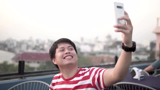 亚洲男子在智能手机上拍照或录像。