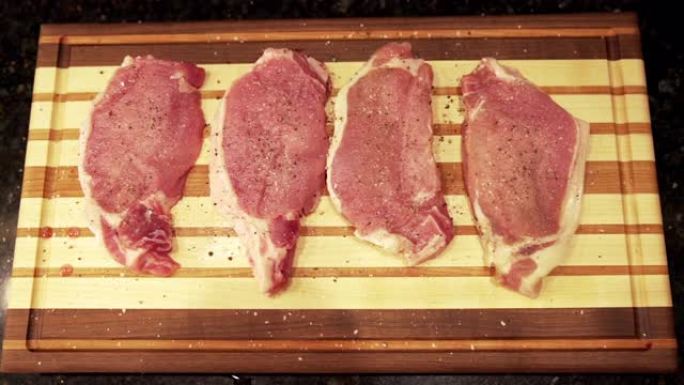 慢动作平放，将新鲜的未煮熟的生去骨里脊肉猪排放在准备烧烤的木制切菜板上