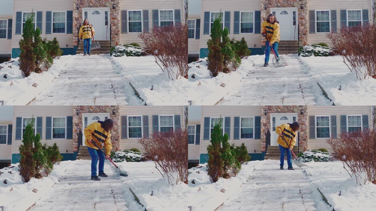 一名成年的50岁长发男子，在一场冬季降雪后，在乡间别墅的前院穿着一条黄色的夹克清洁道。美国宾夕法尼亚