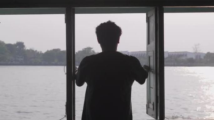 一个年轻的亚洲人站着看着河边的风景。