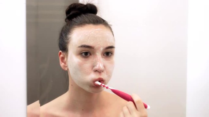 一名年轻女子正在浴室刷牙。镜像中的肖像。