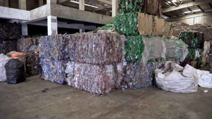 在回收中心等待过程的破碎透明塑料瓶堆叠立方体的背景。