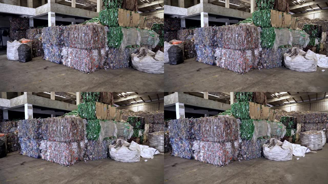 在回收中心等待过程的破碎透明塑料瓶堆叠立方体的背景。
