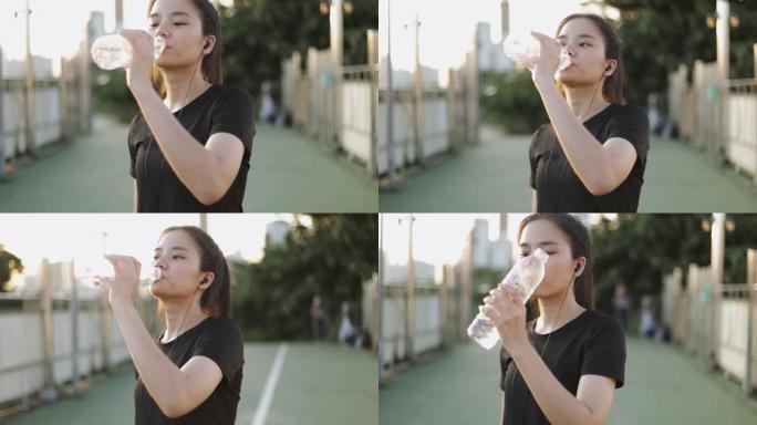 迷人的亚洲女性慢跑跑步后喝水。