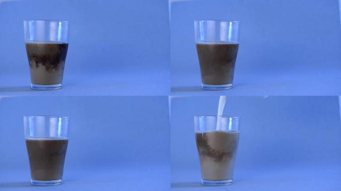 在装有黑咖啡的玻璃杯中，在蓝色背景上添加牛奶，并放置文字