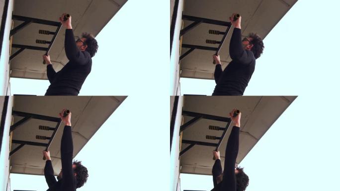 一个戴眼镜的家伙在他公寓的阳台上做引体向上。4k慢速移动