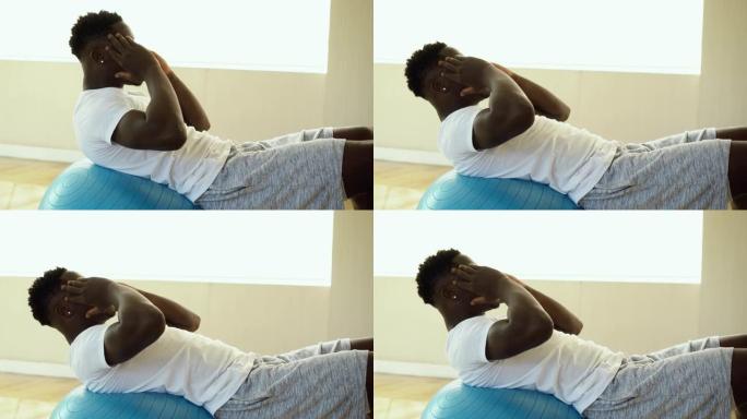年轻的非洲裔美国男子在健身房用瑞士球做仰卧起坐运动