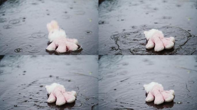 长毛绒的粉红色野兔掉进了水坑。下着大雨。慢动作视频