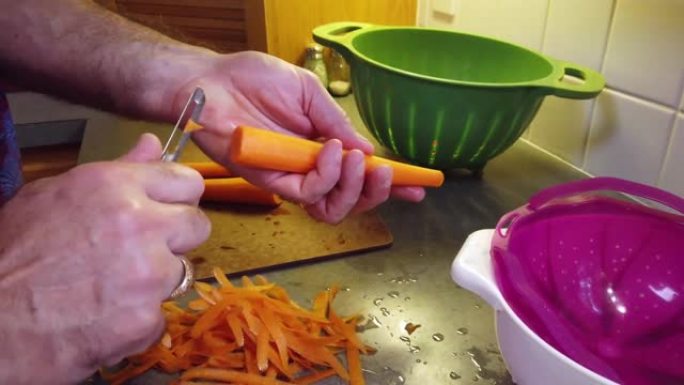 厨房食物准备，剥橙色胡萝卜平移4k镜头的白人男性准备食物作为一顿饭。