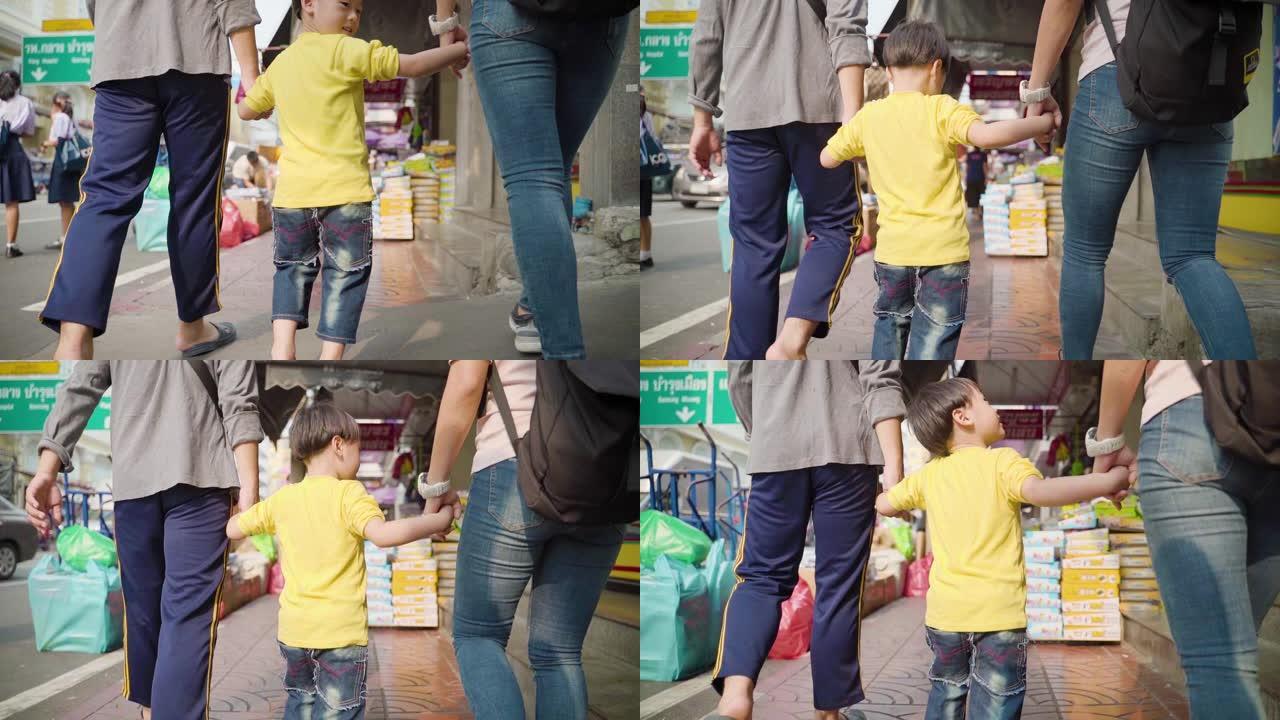 一个小男孩与家人一起旅行并在泰国曼谷的城市街道上行走的慢动作镜头