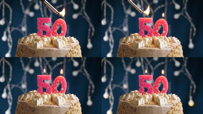 蓝色背景上有50号粉色蜡烛的生日蛋糕。蜡烛着火了。慢动作和特写视图