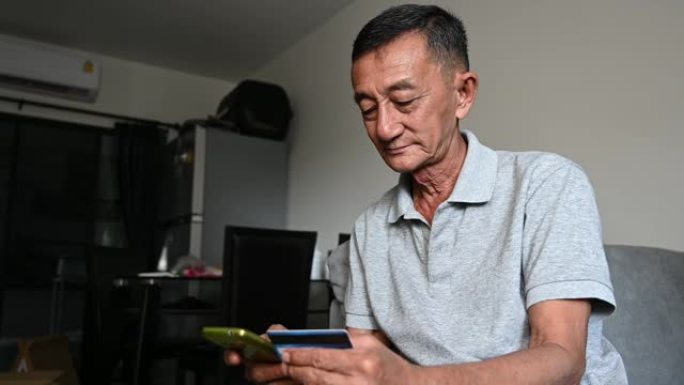 4k亚洲老人肖像使用智能手机和信用卡从网上购买。Hapiness，技术和电子商务老人肖像概念。