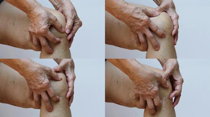 患有右膝疼痛的高级女性，在白色背景下用手按摩，特写 & 宏观拍摄，亚洲身体皮肤部分，保健，关于按摩概