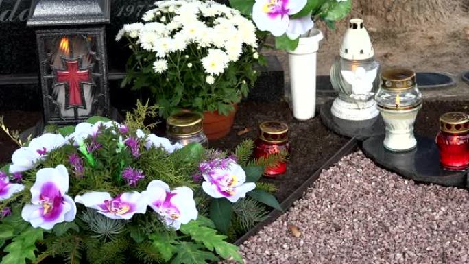 玻璃蜡烛灯和菊花在墓碑上。全景。4K