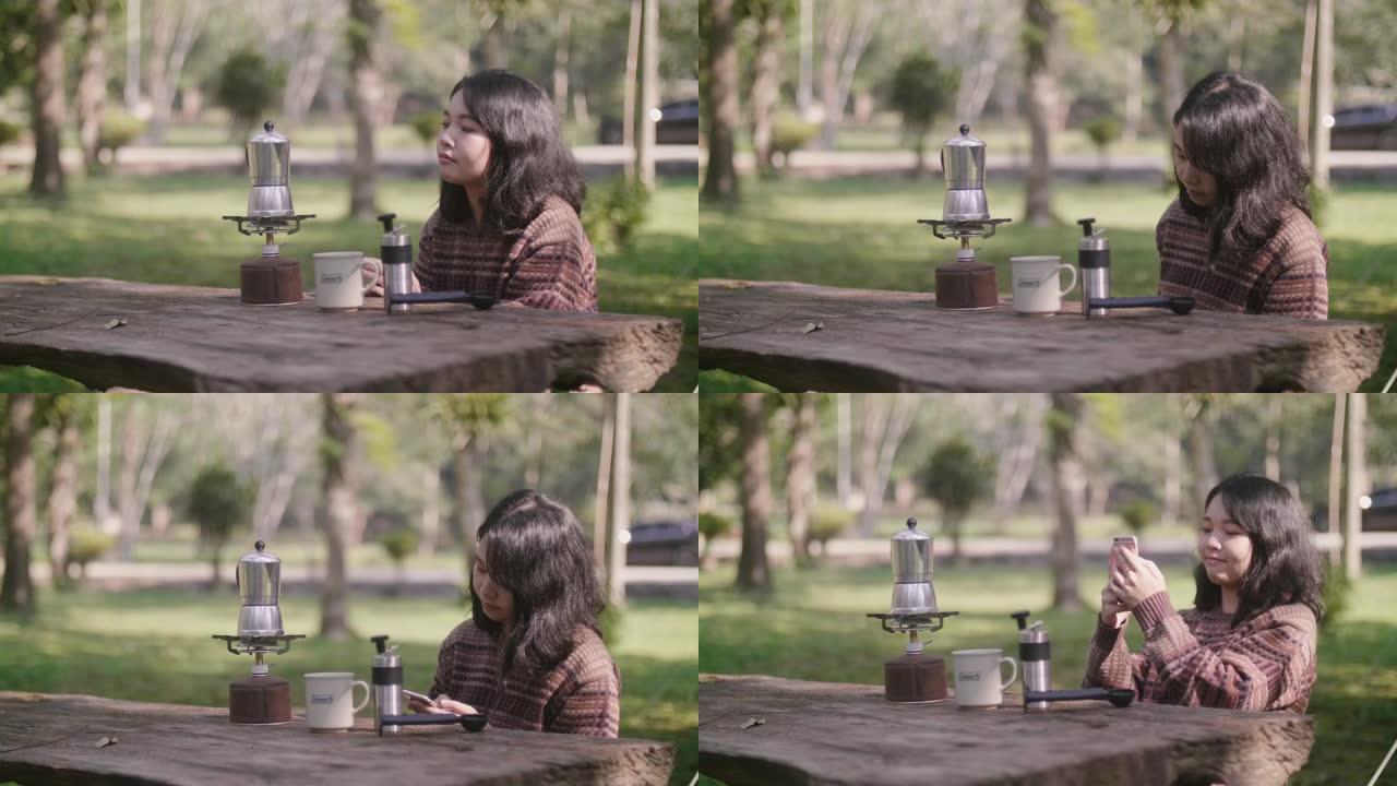 亚洲女孩欣赏大自然的景色，并用智能手机为她的咖啡机拍照。