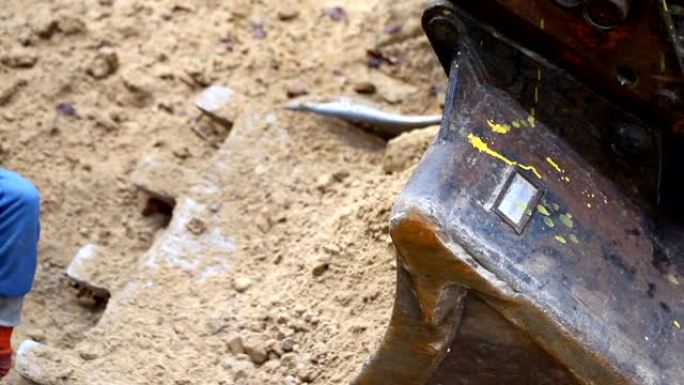 工人用铁锹挖土扔进大钢挖掘机铲斗