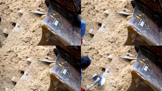 工人用铁锹挖土扔进大钢挖掘机铲斗