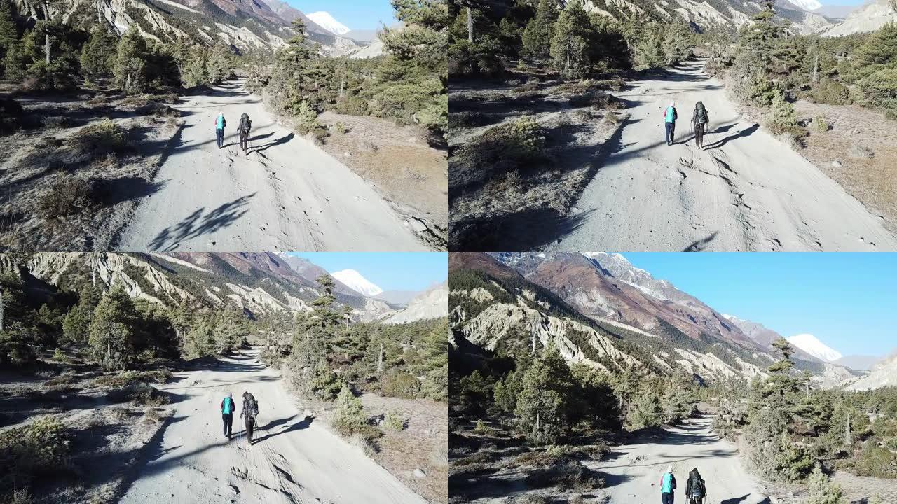 一对夫妇在尼泊尔喜马拉雅山马南山谷的森林中漫步。后面的安纳普尔纳链尖锐而贫瘠的山峰。安纳普尔纳巡回赛